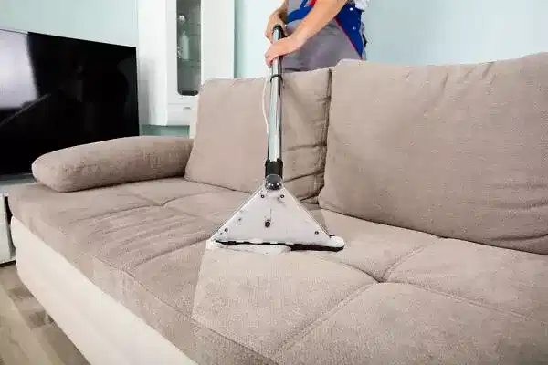 Young Male Worker Cleaning Sofa With Vacuum Cleaner Young Male Worker Cleaning Sofa With Vacuum Cleaner